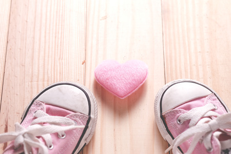 Pink girl's sneakers with pink hearts on a wooden floor, The concept of Valentine's Day.の写真素材