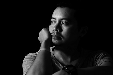 Asian Man in the Dark Looking out the window Looks sad moodの写真素材