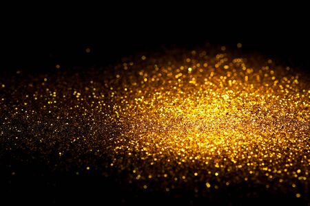 Sprinkle gold glitter dust on a black background with copy space.の写真素材