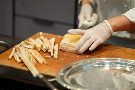 The chef's hands are making ham cheese sandwiches.