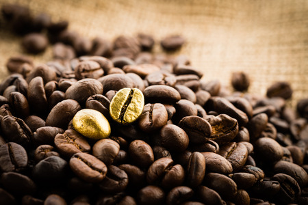 Gold coffee beans on a pile of coffee beans. The concept of luxury is extraordinary.の写真素材