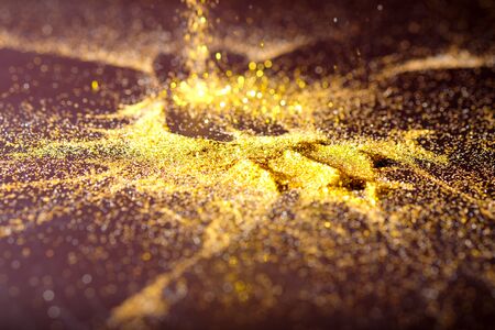 Sprinkle gold dust on a black background with copy space