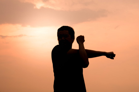 Silhouette of a man Stretch the muscles exercises on landscape sunset background