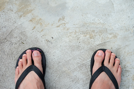 Feet of men wearing black sandals on the cement floor