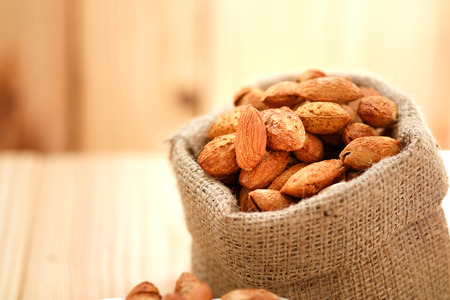 Almond nuts in the shell In sackcloth on wooden background