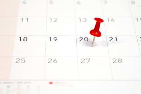 Embroidered red pins on a calendar on the 20th with selective focus