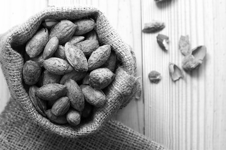 Almond nuts in the shell In sackcloth on wooden background, Black and white toneの写真素材
