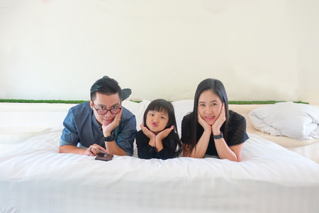 Asian Family Lovely lie about puckering lips and Pose hands on chin on white bed with copy spaceの写真素材