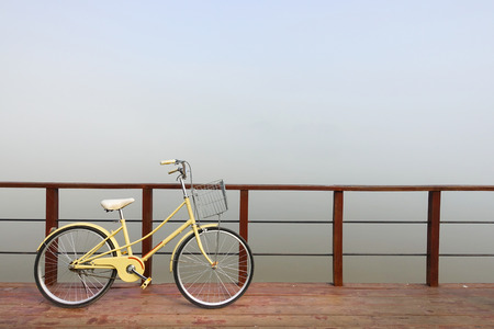 Vintage bicycle leaning against a wooden fence River in the foggy park.の写真素材
