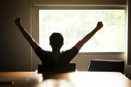 Asian men are holding their arms and fists to loosen their gaze out of the morning window, ready for the first day's work.の写真素材