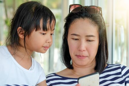 Asia Mother and daughter are watching mobile while travelingの写真素材
