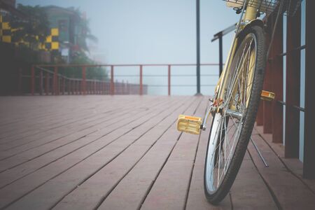 Vintage bicycle leaning against a wooden fence River in the foggy parkの写真素材