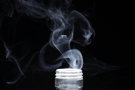 Smoke or abstract steam from the bottle on a black background.の写真素材