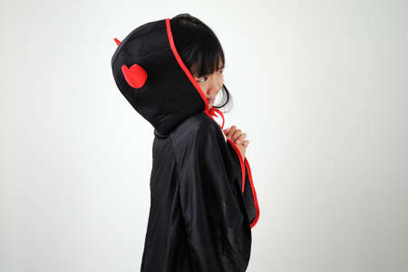 Asian child girl in demon costume holding black and red trident, Happy halloween concept