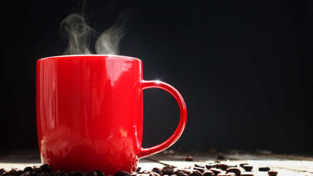 Coffee or tea with hot steam in the morning in red glass on a wooden table.の写真素材