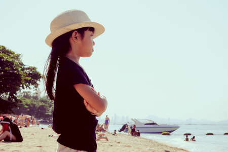 An Asian girl wearing a hat, she is sad and thinking what she is while on the seaside.の写真素材