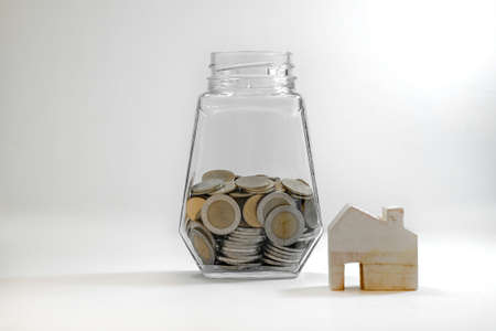 Coins in a dozen glass and wooden house models on a white background, concept save money for Repair...
