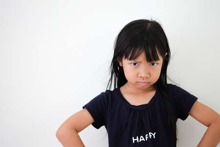 Asian girl shows anger on the face with arms hands on hips on a white background