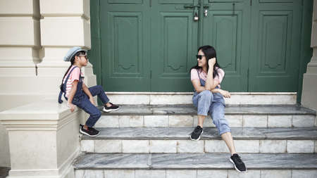 Asian child girls wear denim bibs and fashion post caps with the mother in front of the old green door.の写真素材