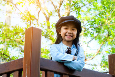 Asian girl smiling face wearing a denim shirt and a hat standing in the outdoor gardenの写真素材