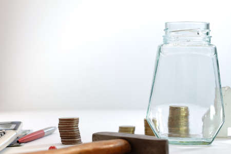 Coin stacked, glass jars, pens and calculators placed on a white background, images for financial...