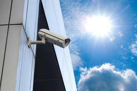 CCTV is attached to the wall next to the outdoor home on sky background with copy space
