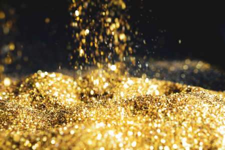 Sprinkle glitter gold dust sand in the dark textured abstract background elegant for Merry christmas and Happy new yearの写真素材