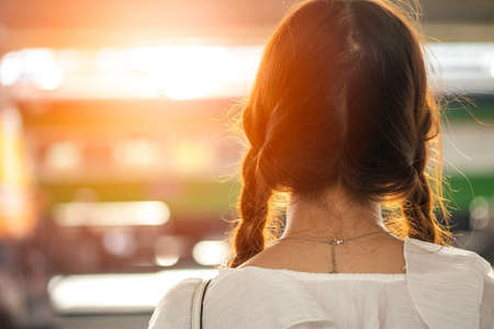 Asian woman with long hair, pigtail on both sides. Standing, looking back at the train station, waiting for someoneの写真素材