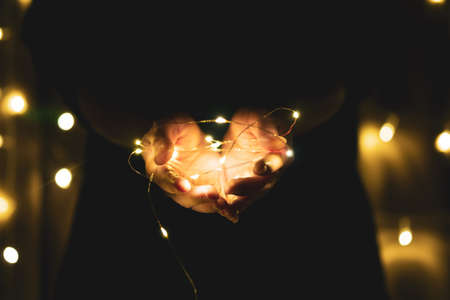 Christmas and Happy New Year decorations lighting in the hands of young womenの写真素材