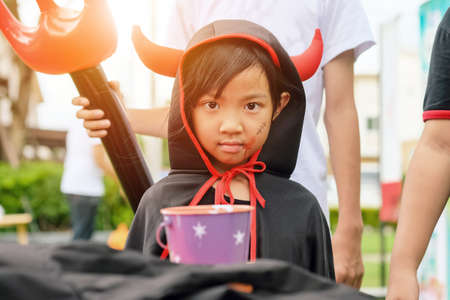 Asian child girl in demon costume black and red tone, Happy halloween party concept