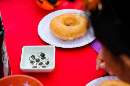 Donuts are on a plate placed on a table decorated for a happy Halloween partyの写真素材