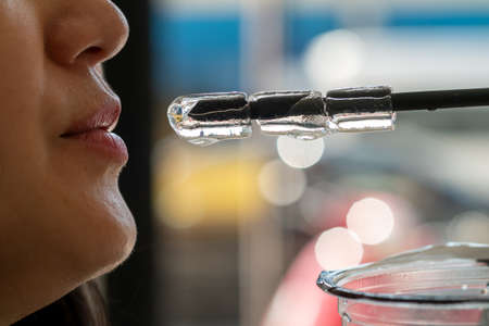 The woman's mouth is about to eat the ice that is inserted into the straw.の写真素材