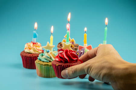 Hand holding a Variety of colorful cupcakes with candles to celebrate the light for Merry Christmas...