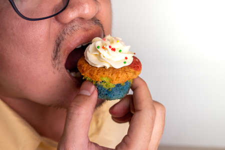 Asian men wearing glasses eating deliciously cupcakes