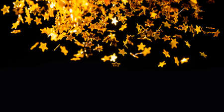 Sprinkle gold star dust glitter on a pile black background with copy space for merry christmas and happy new year, texture Luxury and elegant decorationの写真素材