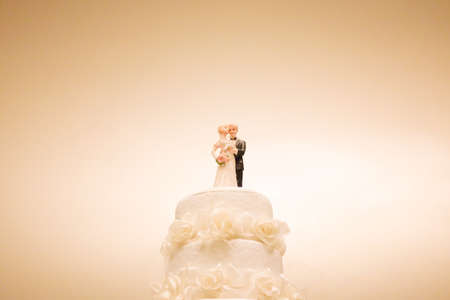 Bride and groom doll on the white cake on the wedding dayの写真素材