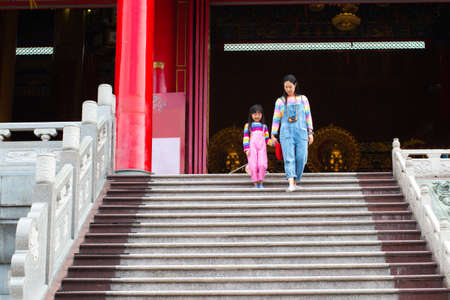 Asian mother and daughter are wearing jeans, T-shirts of many colors, smiling mood and walking in temples, the concept of family lifestyle.の写真素材