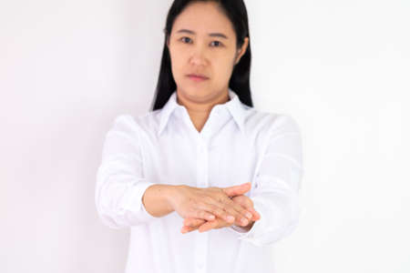 An Asian woman wearing a white shirt is washing her hands with alcohol gel to protect against corona virus or covid 19 on a white background.の写真素材