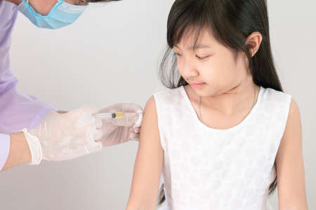 The doctor is injecting medicine for treatment or a vaccine to prevent corona virus or Covid 19 in the arms of an Asian girl.の写真素材