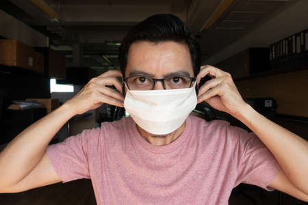 Asian men wearing pink T-shirts and wearing glasses are showing the right masks to prevent germs and...