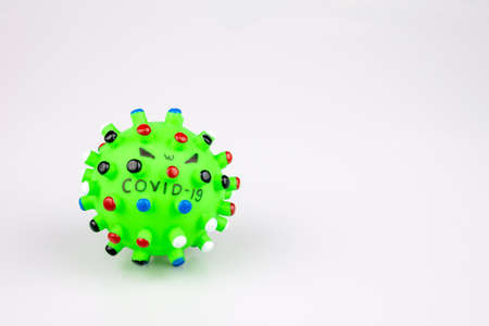 Green rubber ball with colorful thorns writing a virus Covid-19 on a white background