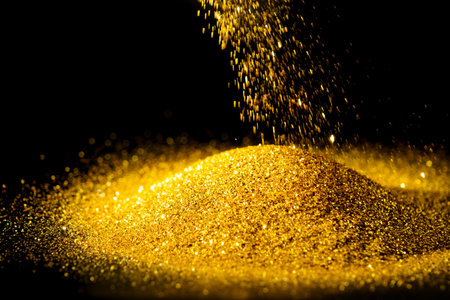 Sprinkle the glittering gold powder on the ground and black background.の写真素材