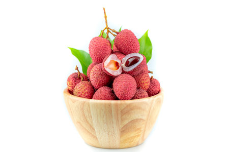 Lychee Hong Hui in a wooden bowl with branches and green leaves on a white backgroundの写真素材
