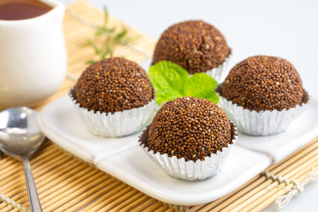 Perilla seed mixed with Jaggery palm sugar and mold into a ball place on a white plate decorated with mint leaves on a bamboo mat with spoons and forks.の写真素材