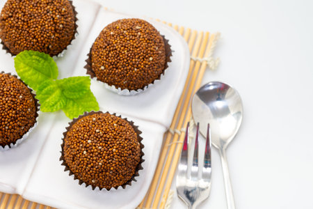 Perilla seed mixed with Jaggery palm sugar and mold into a ball place on a white plate decorated with mint leaves on a bamboo mat with spoons and forks.の写真素材