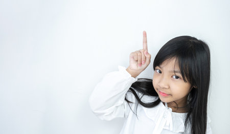 Asian child girl with white shirt pointing up into the copy empty spaceの写真素材
