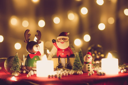Santa Claus doll, pine tree, deer, snowman and gift box merry Christmas decoration on a bokeh light background with copy spaceの写真素材