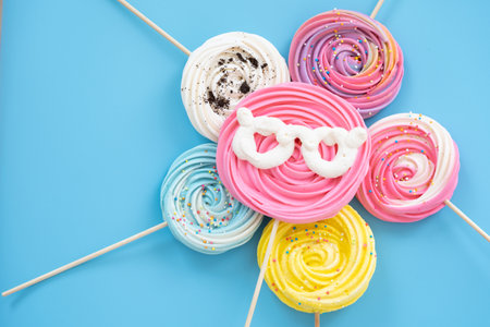 Lollipop Meringue Dessert Sprinkled with blue bow on a blue background with colorful toppings.の写真素材