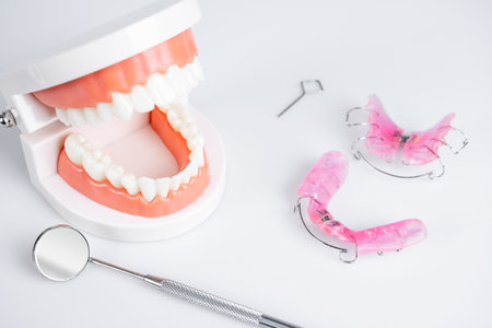 Removable orthodontic or orthodontic devices for children with crooked teeth, model teeth and dental mirror on white background.の写真素材
