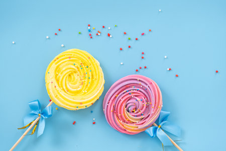 Lollipop Meringue Dessert Sprinkled with blue bow on a blue background with colorful toppings.の写真素材